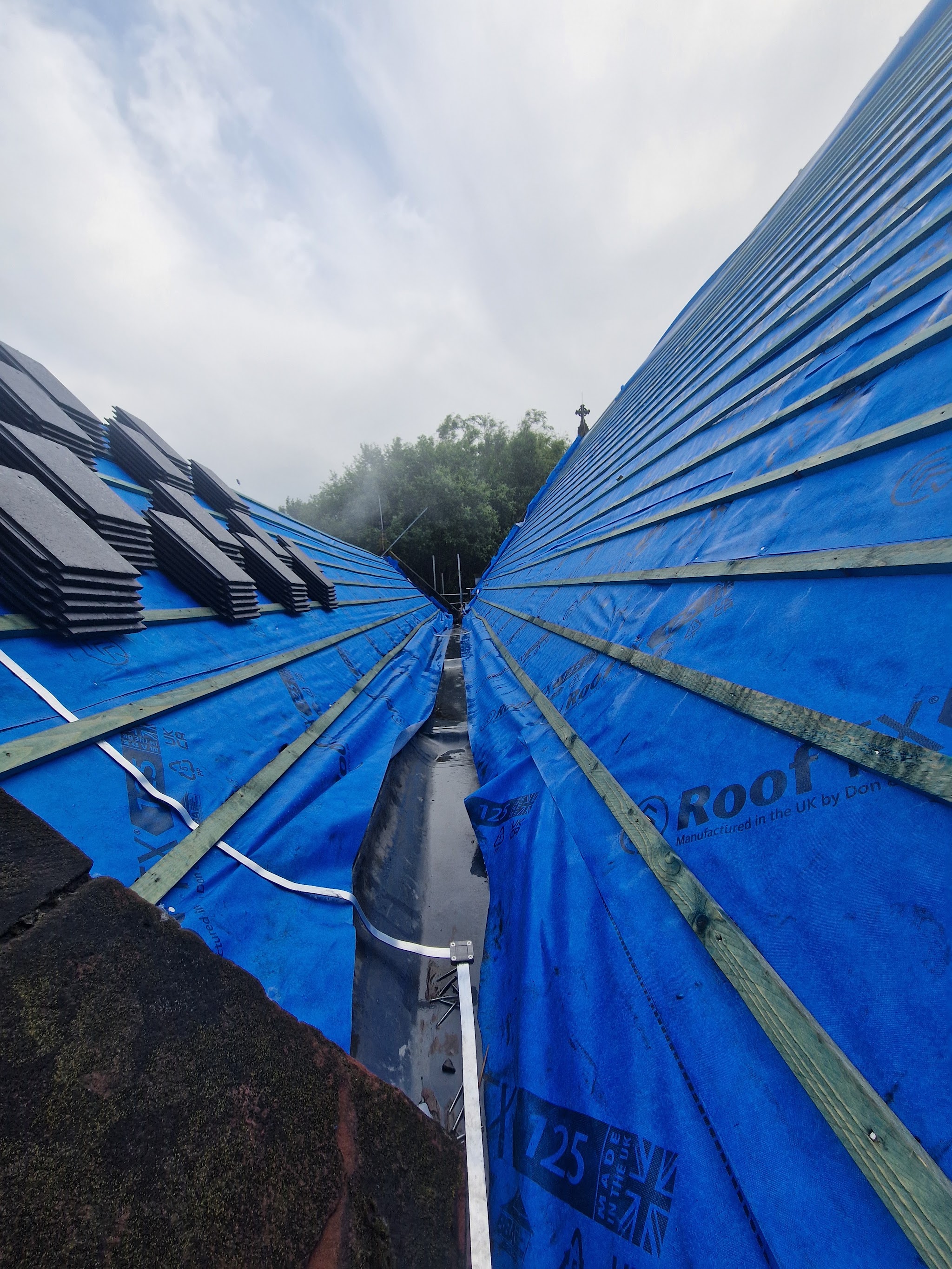 A roof valley lined and battened with slates stacked ready to lay