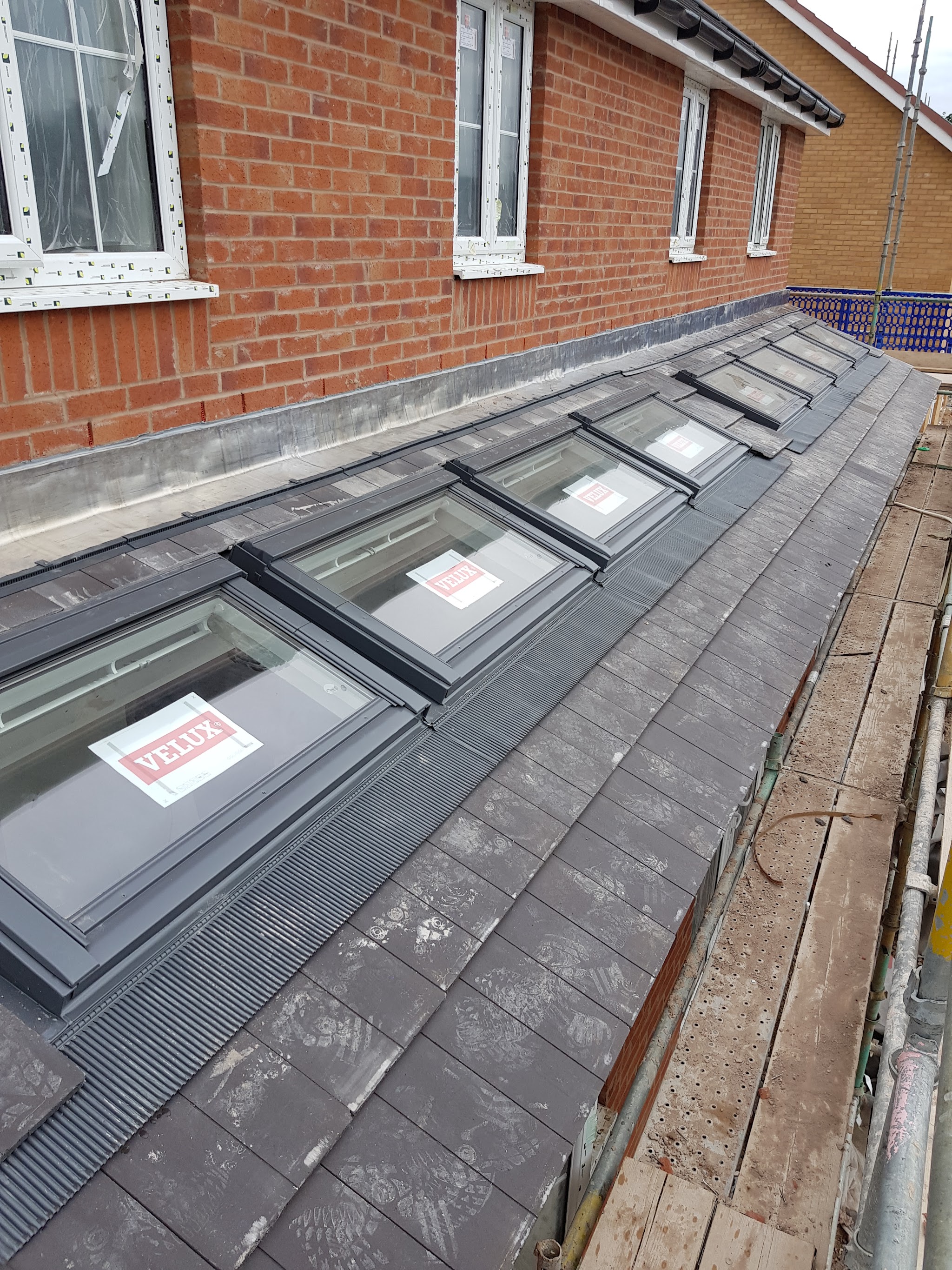 Four VELUX roof windows fitted in a new slate roof against a brick wall